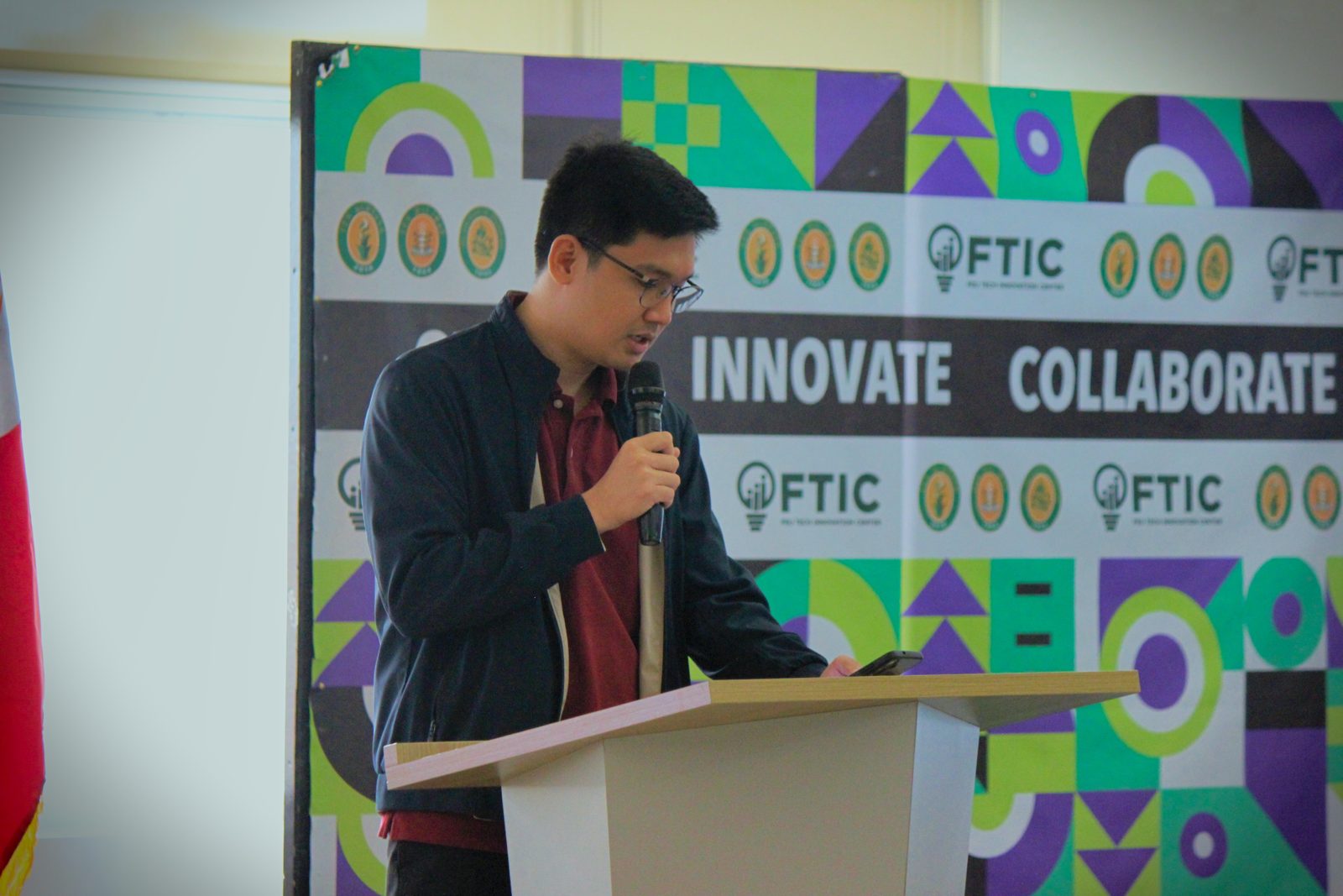 Speaker at the Create & Conquer 2026 podium with the FTIC Innovate Collaborate backdrop