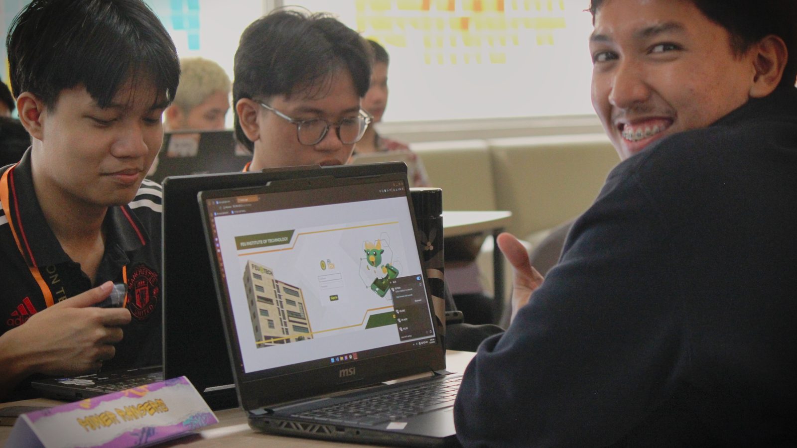 Team showing their project build on a laptop at Create & Conquer 2026